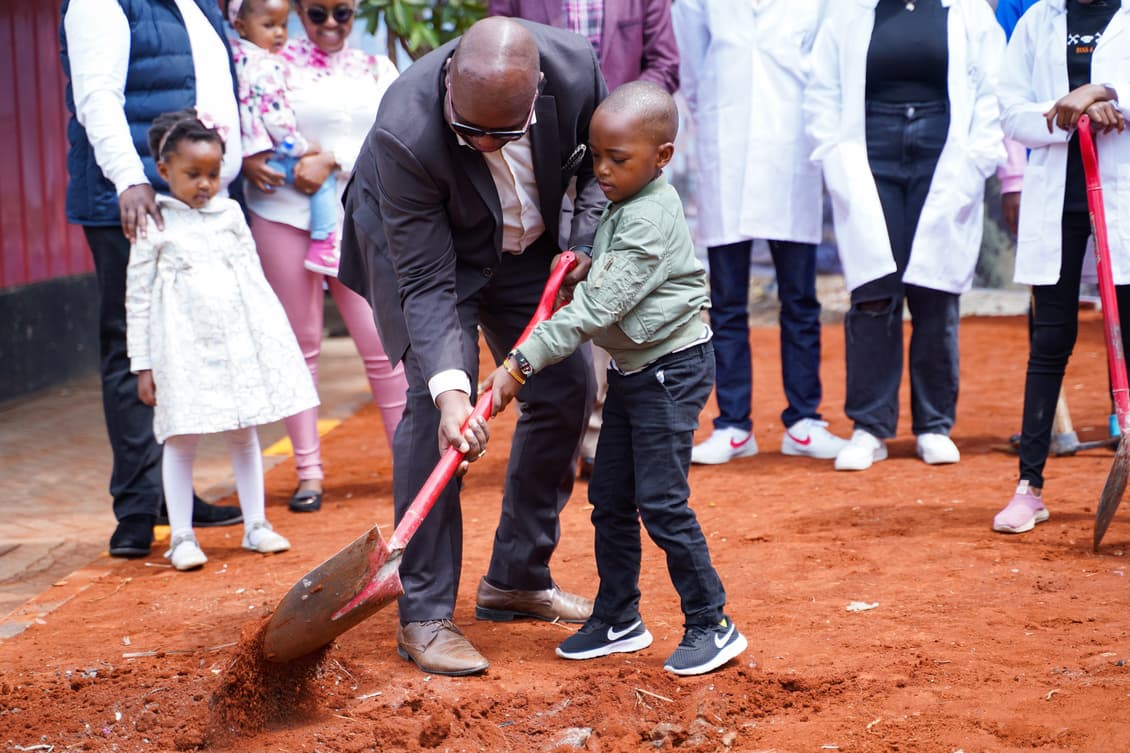Child turning soil with Bishop Anduvate at the groundbreaking